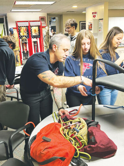  Ryan Krichiver, mobile integrated health coordinator for the Sterling Heights Fire Department, helps Henry Ford II High School sophomore Aviana Bradford with her knot-tying skills. 