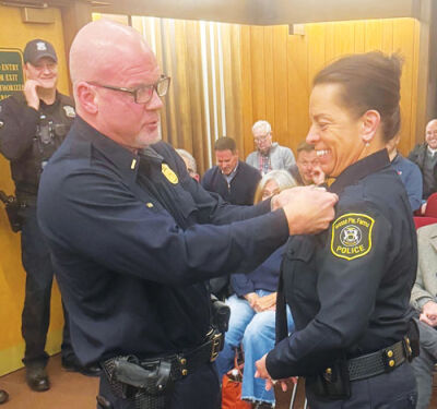  Detroit Police Department veteran Jim Cashion pins the lieutenant badge on his wife, Veronica Cashion, as she is promoted to a new rank in the Grosse Pointe Farms Public Safety Department.  