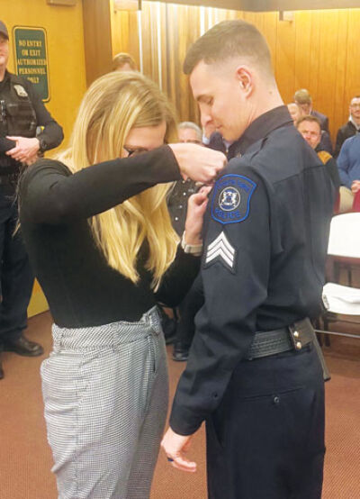  Grosse Pointe Farms public safety officer Will Madsen has his new sergeant badge pinned to his uniform by his wife, Sarah. 