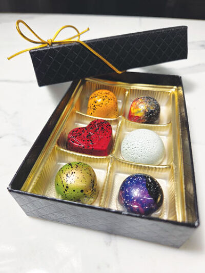  A package of bon bons from Asterism Artisan Chocolate includes  space-themed treats alongside a heart-shaped bon bon. 