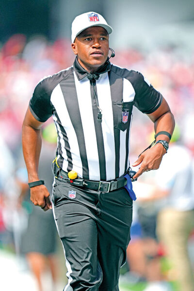  Shawn Smith runs on the field wearing the solid-white NFL referee cap in a game. 