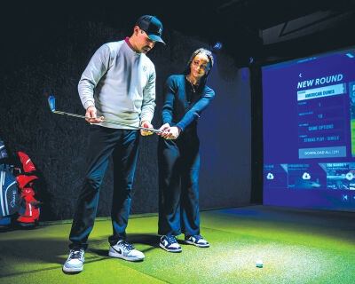  A golfer gets tips on her swing at a Back Nine indoor golf facility. 