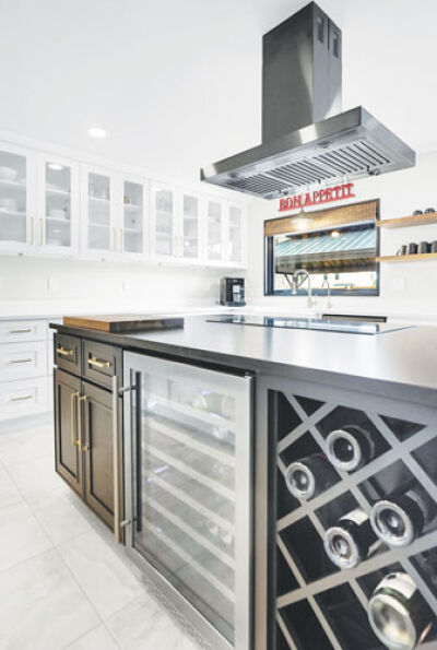  A wine rack and beer fridge with a few bottles and cans are visible underneath a kitchen island with only a cutting board on top of the island and nothing on the kitchen counters in this ready-to-sell home in Troy.  