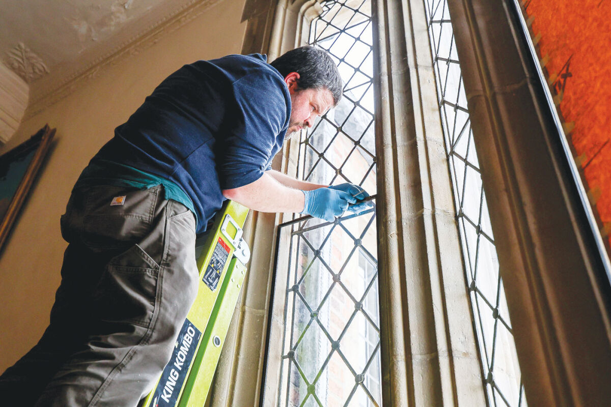  Josh Hanley places a panel with UV protection over the windows. A crew of artisans from Omnibus Studios visited Meadowbrook for the final phase of the window repairs. Omnibus Studios also repaired the stained glass that was damaged by vandals.  