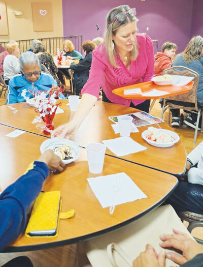 A member of the Novi Choralaires serves ice cream to a group of seniors.