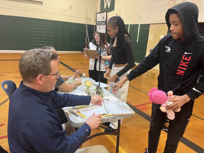 Eight grade student Chris Sims, right, decides on what house to buy from Center Line Public School elementary instructional coach Steve Haney. 