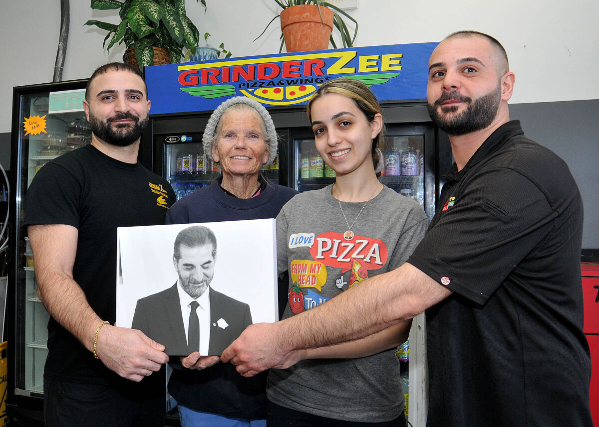  Max Orow, left, and his brother Austin, right, hold a photo of their late father Wally, the founder of GrinderZ Pizza, at the Hazel Park location. Joining the Orow brothers are GrinderZ staff members Debra Voss, center left, and Danela Benyamen.  