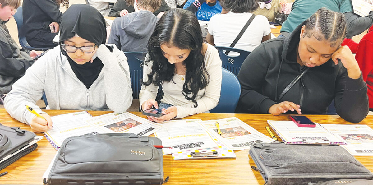  Students, left to right, Rizwana Chowdhury, Thakwa Khanom and Ariyannah Hamilton look over their budget summaries in the Wolfe Middle School  library Feb. 23.  