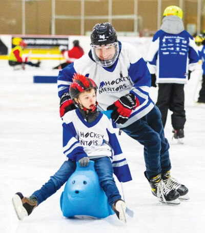  Hockey Mentors founder Wyatt Lucas skates with a participant in an event from last year. 