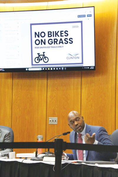  Trustee Shannon King speaks to the Clinton Township Board of Trustees on March 16 about an ordinance regulating e-bikes on township property. Presented in the background are signs that could be displayed in township parks to help educate parkgoers about proper e-bike etiquette.  