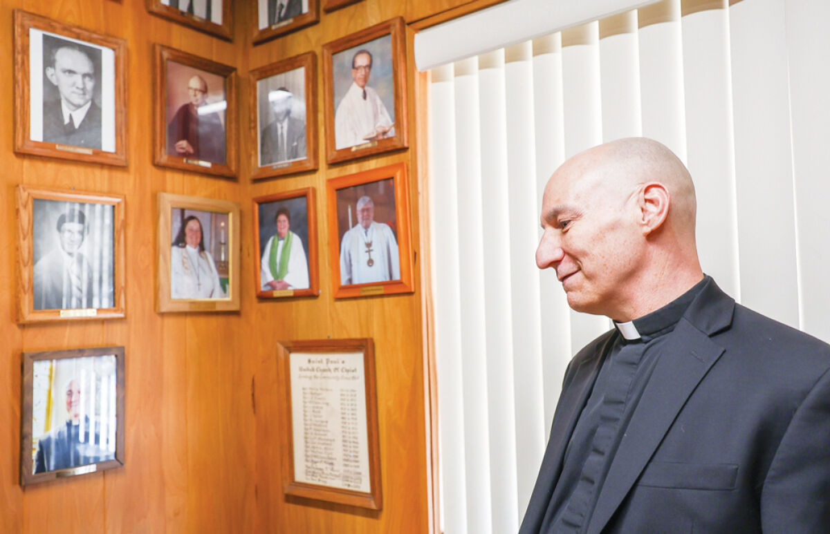  The Rev. K.C. Lazzara views photos of the pastors at St. Paul United Church of Christ. “I’m hoping that the way I texture my service with scripture, with anecdotes, with quotes, everyone takes a little something,” he said.  
