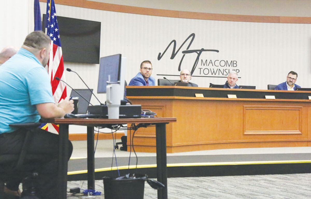  Planning Director Josh Bocks, left in blue, speaks to the Macomb Township Board of Trustees about a corridor improvement authority for the Macomb Town Center on March 11. 