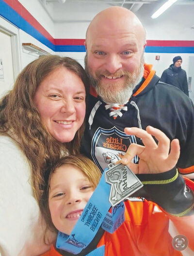  Chmiel and his wife, Dawn, celebrate with his son, Griffin, after his team performed well in a hockey tournament this past December. 