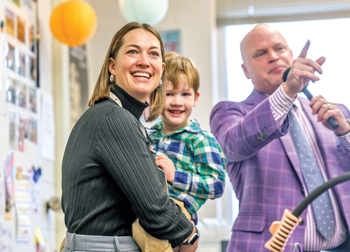  Christina Rick, an English language development teacher at Troy High, is surprised with the Oakland Schools’ High School Teacher of the Year Award March 18. Joining her for the occasion is Troy Schools Superintendent Richard Machesky and Rick’s son, 4-year-old Oscar Rick-Metz. 