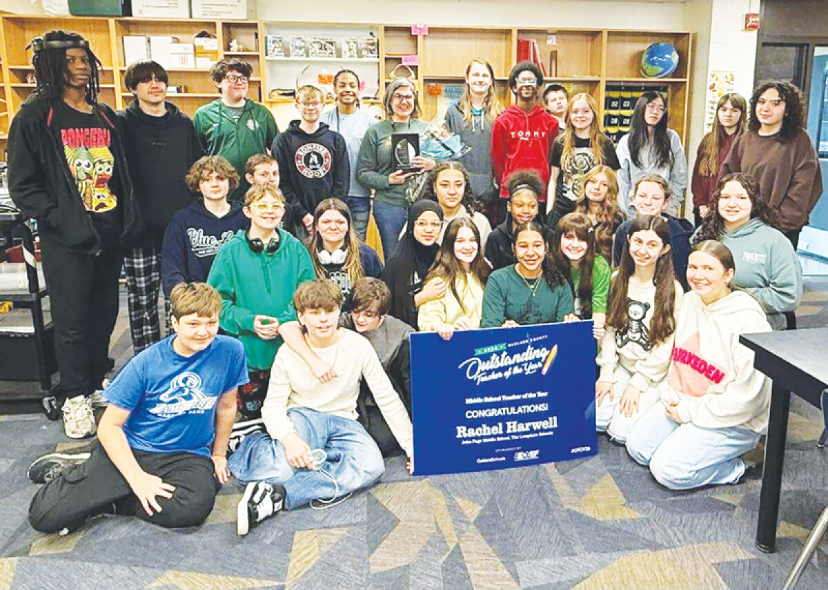  Rachel Harwell’s class gathers around a sign celebrating her award for Oakland County Middle School Teacher of the Year. 