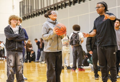  Different stations in the gym were set up that simulated dangerous driving scenarios, including wearing “drunk goggles” while making free throws at the basketball net. Pictured is sophomore Corey Strong, right, directing freshmen Kelli Craddick at the free throw line.  