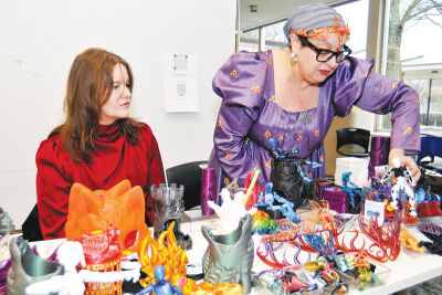  Lawrence Tech student Kaitlyn Fitzpatrick, left, and Lawrence Tech math professor Yelena Vaynberg, right, work a craft table. The Lawrence Tech 3D Printing Club created multiple fantasy and role playing items for sale at the convention. 