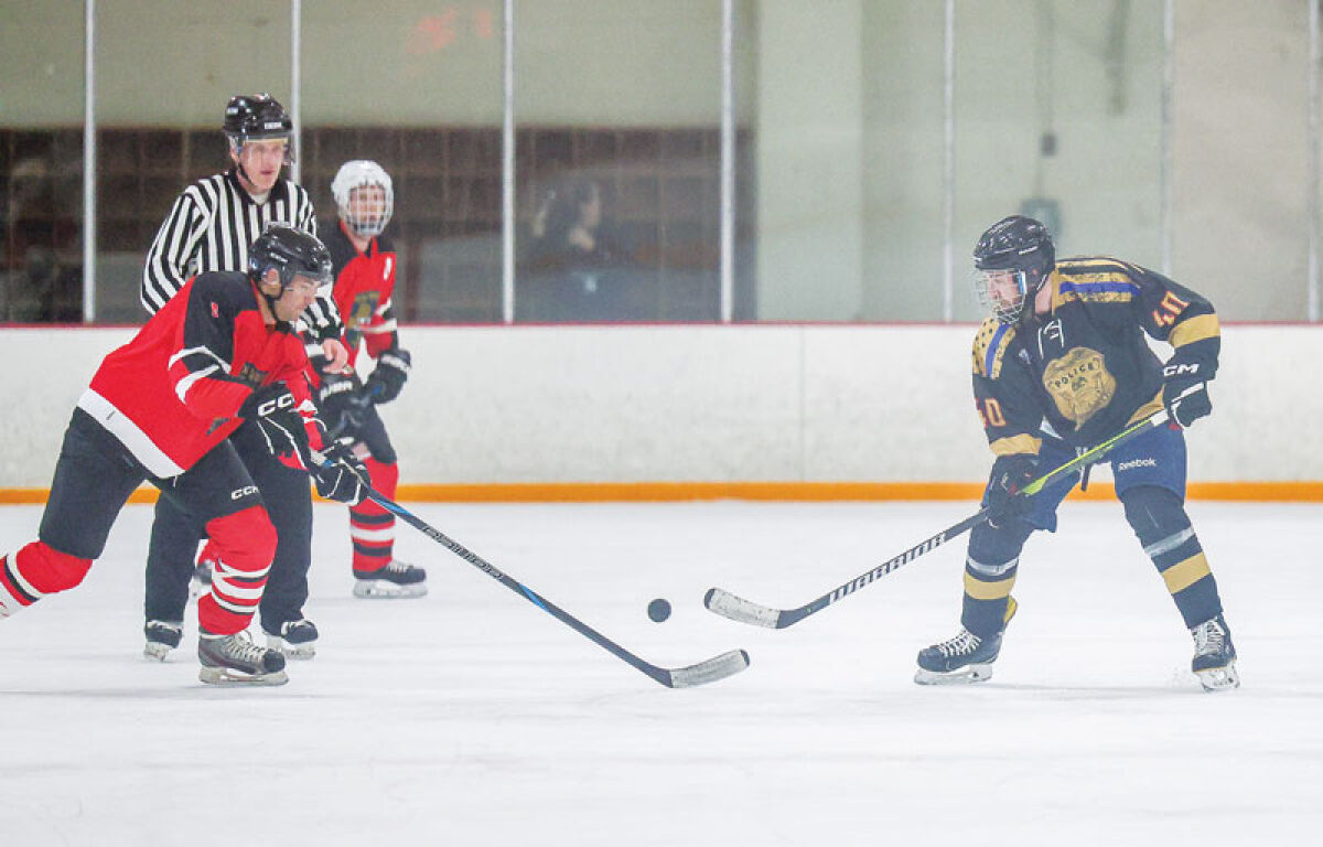  Charles Kassley, No. 8 for the Fire Department, and Alex Lang, No. 40 for the Police Department, go after a loose puck at the Guns and Hoses charity hockey game April 19 at the Southfield Ice Arena. 