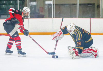  Brendon McDonald, No. 22 for the Fire Department, goes after the puck as Aaron Riley, goalie, No. 29 for the Police Department, makes a save. 