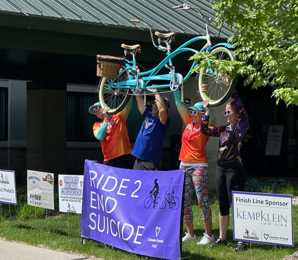  Participants hold up a tandem bike after completing a past Ride 2 End Suicide bicycle ride. 