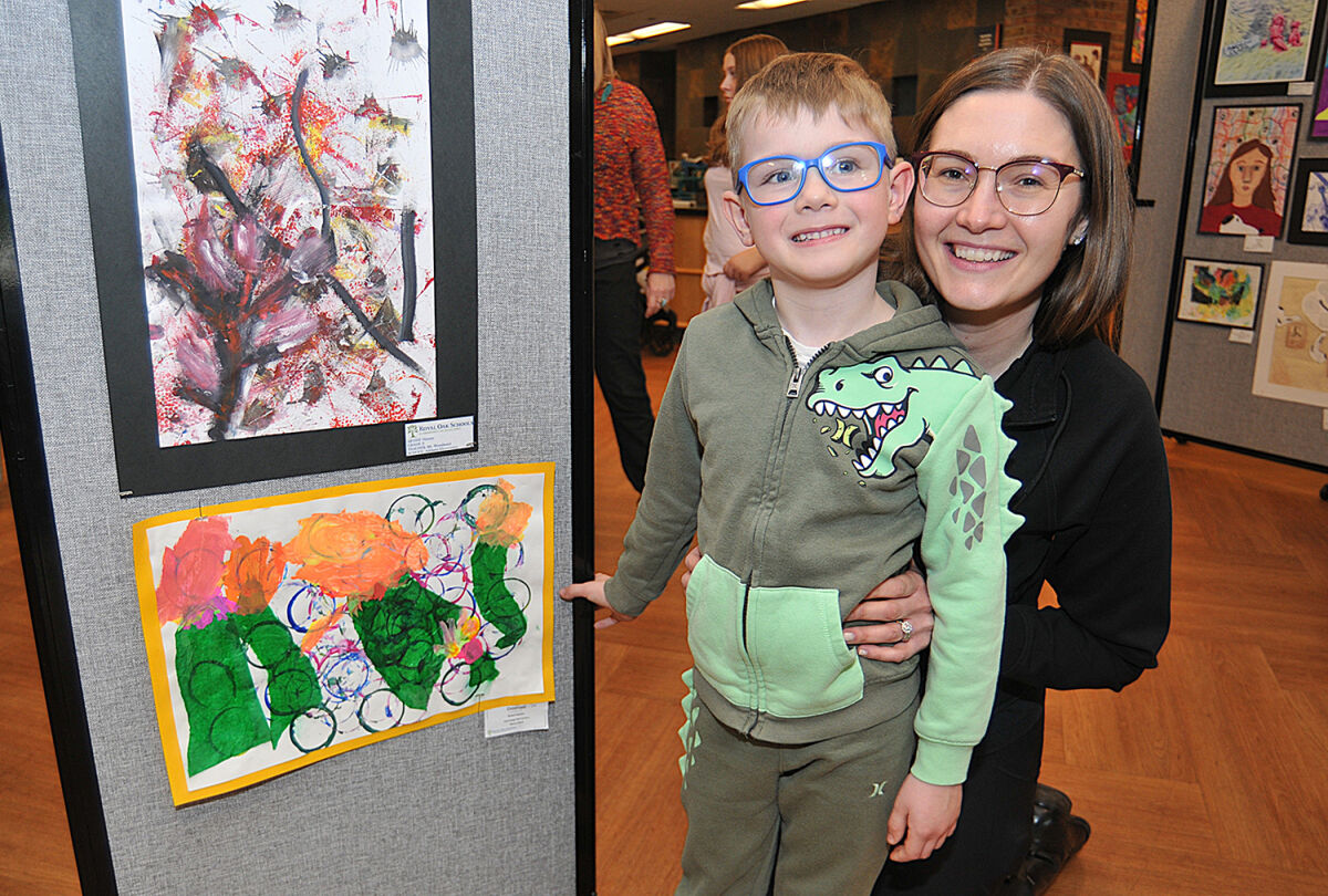  Five-year-old Dashiell Neumann is joined by his mom, Ashly, at the student art show. Dashiell’s painting is at the bottom with the orange trim.  