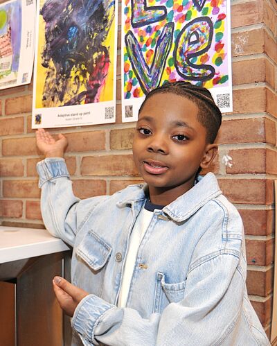  Fifth grader Austin Burnett points to his painting on display inside the Royal Oak Public Library.  