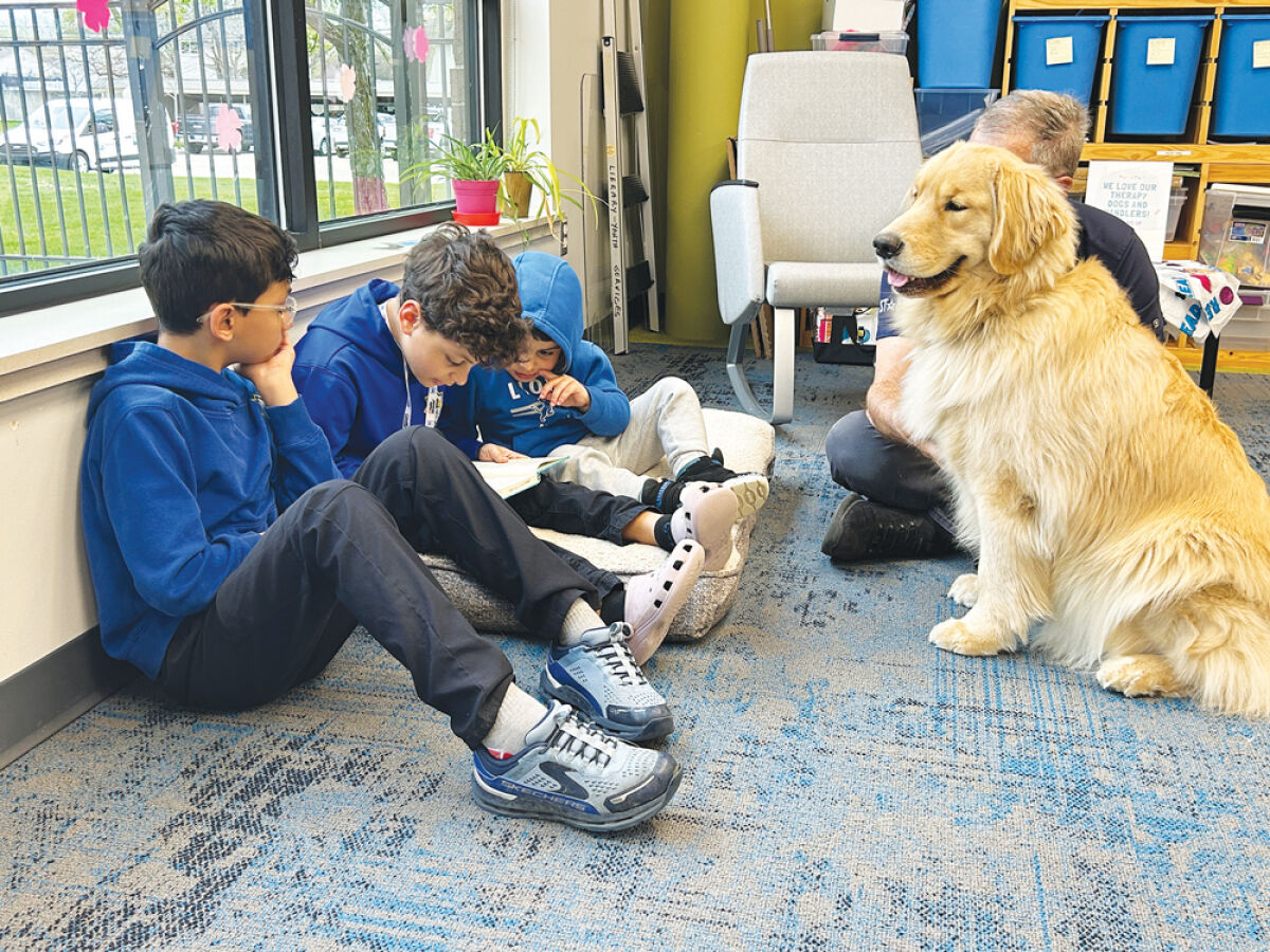  Eight-year-old Edrees Chmeiseh, center, reads a story to therapy dog Oliver and his owner, Ken Hobig, at the Sterling Heights Library. Edrees is flanked by his brother Zackariah, left, and Haroon. 