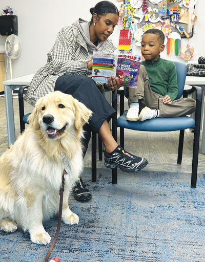  Oliver, a 2-year-old golden retriever, listens as  Alexa and Cortez Settles participate in the Sterling Heights Library’s Paws for Reading program. 