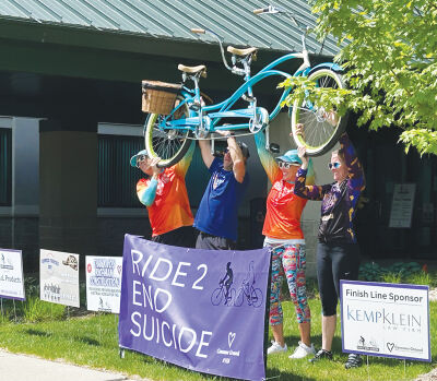  Participants hold up a tandem bike after completing a past  Ride 2 End Suicide bicycle ride. 