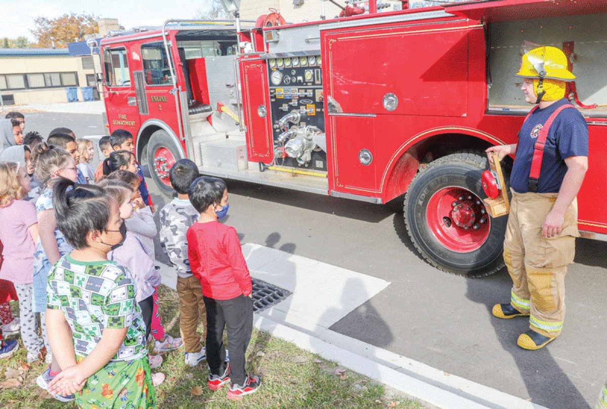  On Oct. 25, students in the Center Line High School firefighting program visit Roose Elementary School. Here, senior Skyler McAlpine talks about the bell that is used to start a timed practice run for getting into gear. 