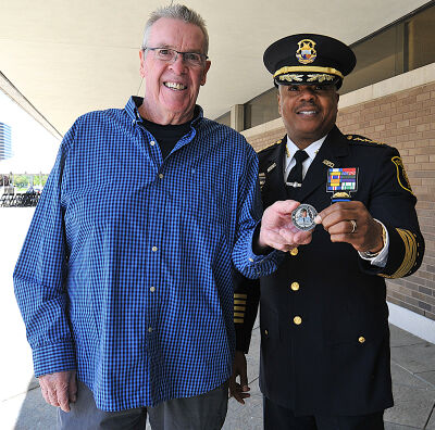  Southfield Police Chief Elvin Barren, right, and Dennis McMahon, left, hold a memorial challenge coin depicting fallen Southfield police officer James McMahon. 