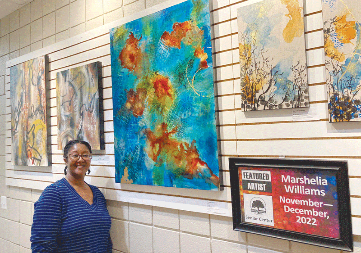  Marshelia Williams, the featured artist at the Shelby Township Senior Center for the months of November and December, poses for a photo with some of her artwork that is on display at the center. 