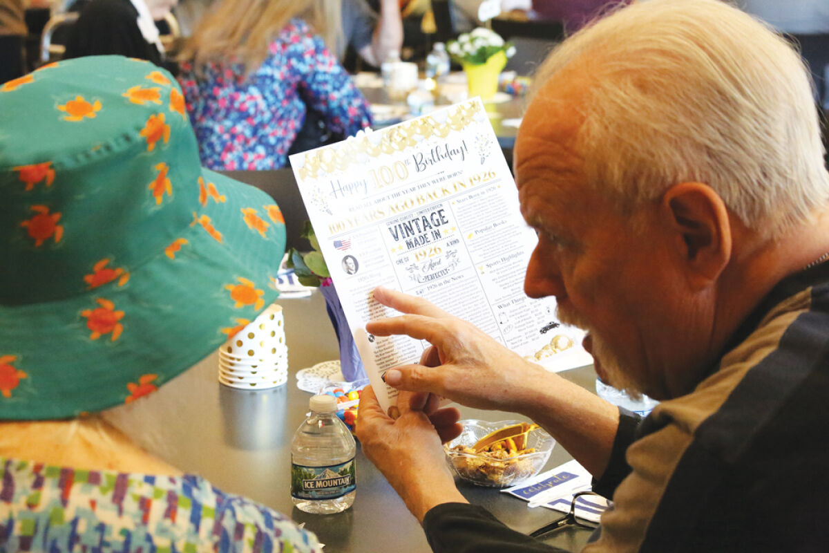  Attendees of the May 8 100 Club celebration look over a printout of 1926 facts. 