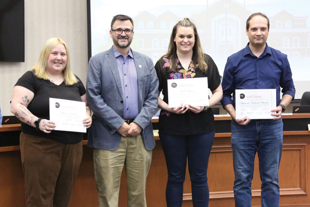 The top three finalists of Macomb Township’s 2026 photo contest — second place Katherine Barraco on left, winner Nicole Simon in the middle and third place Otavio de Andrade Oliveira on the right — pose with Township Supervisor Frank Viviano and certificates at the April 22 Macomb Township Board of Trustees meeting. 