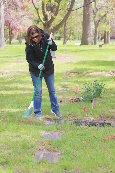  Sharon Stanton, of Royal Oak, sweeps at a gravesite. 
