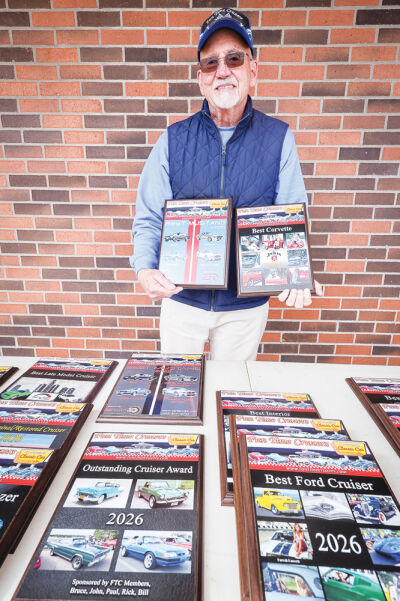   Ken Savage holds up two of the 16 customized award plaques that are given out each week at the Fun Time Cruzers Car Show in the Napa Auto Parts parking lot, located at 48081 Van Dyke Ave. in Shelby Township. 