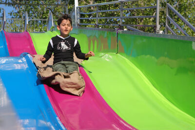 A child smiles as he slips down a slide at the Shelby Township Down Home Days Festival in 2024.