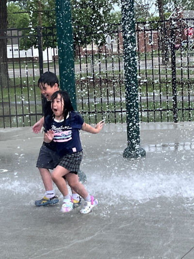 Princeton Kue, 9, and Ariel Kue, 7, run away after the dump bucket drenched them.