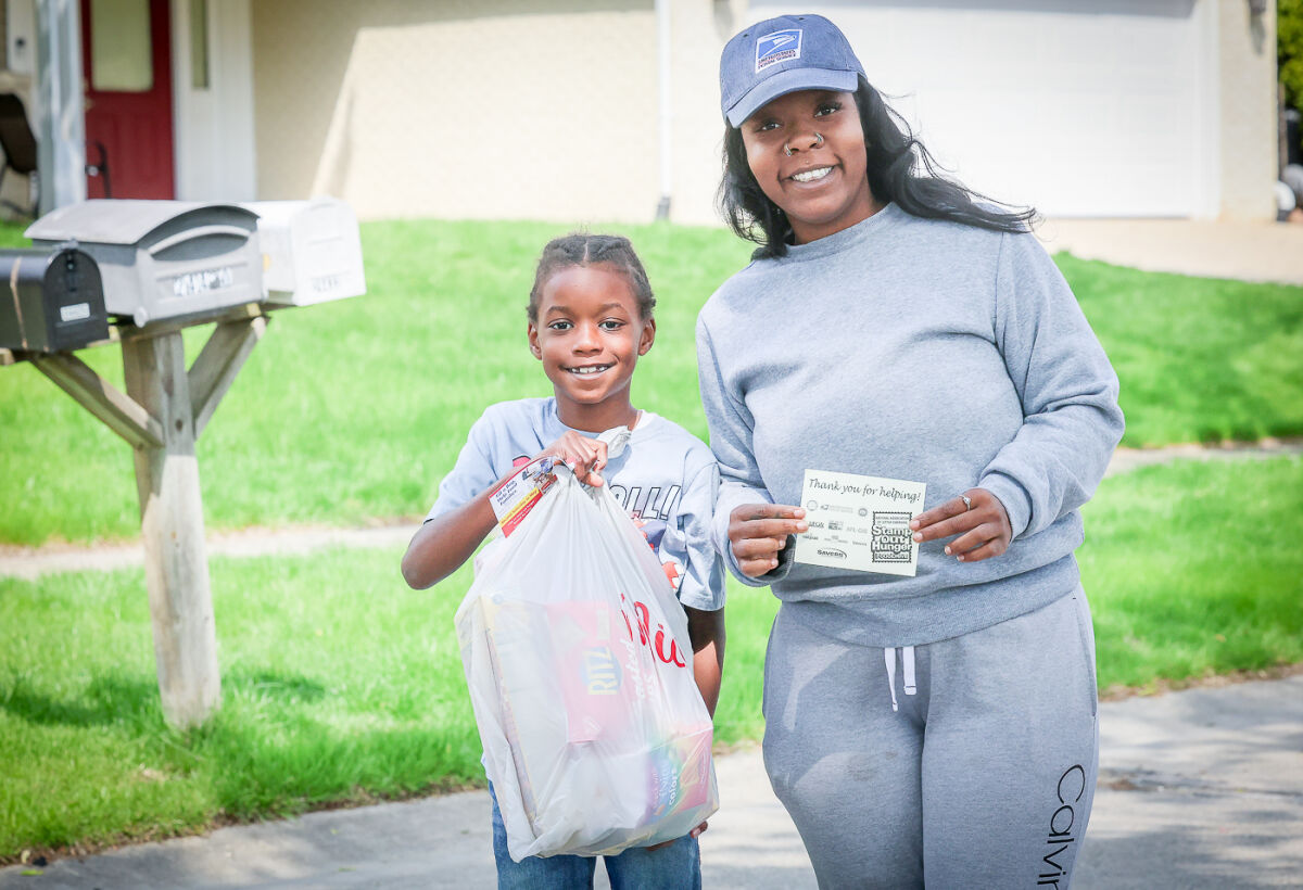  U.S. Postal Service letter carrier Christina Davis-Brown and her son, Dylan, 8, collect food and leave thank-you notes in Novi May 9 during the Stamp Out Hunger food drive in Novi. 
