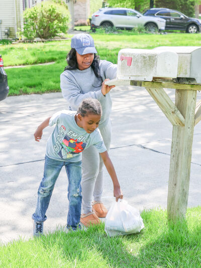 Dylan collects the food while his mom leaves a thank-you note at a Novi residence.