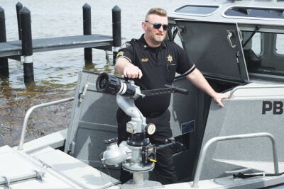  Sgt. Jamie Bagos of the Macomb County Sheriff’s Office Marine Division stands with the water cannon on a Marine Division patrol boat. The cannon pumps water from Lake St. Clair to extinguish fires. 