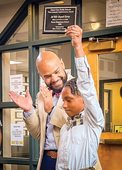   Roose Elementary fourth grader Ja’Mir Royal-Terry holds up his Turn Around award as social worker Derrick Jackson applauds 