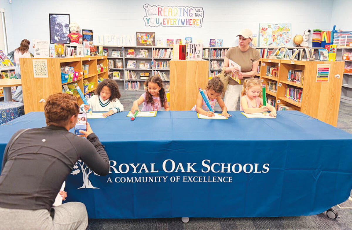  Incoming kindergarten students sign their “Certificate of Excitement” with large pencils. 