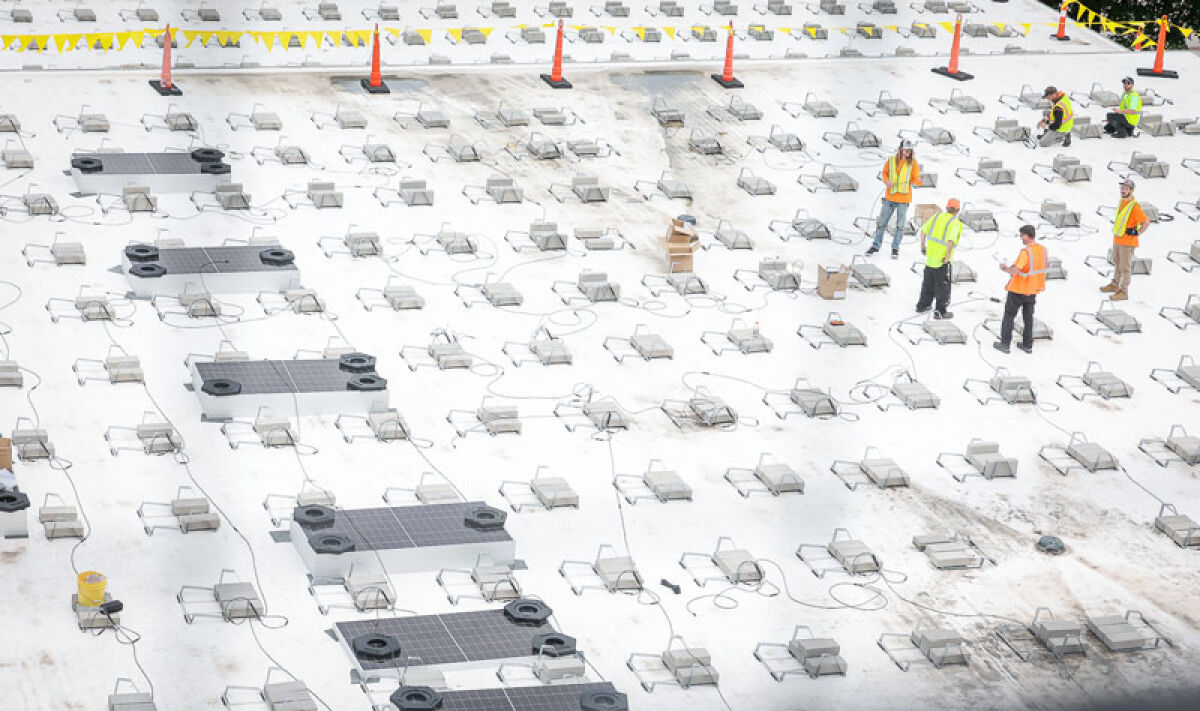  Workers install solar panels May 20 on the roof of the Royal Oak Public Library. 