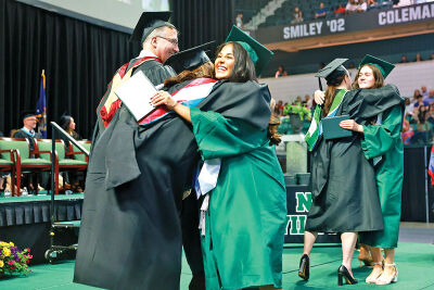  Anika Patel, student council executive board president, embraces one of her educators as she receives her diploma May 17 at the George Gervin GameAbove Center in Ypsilanti. 