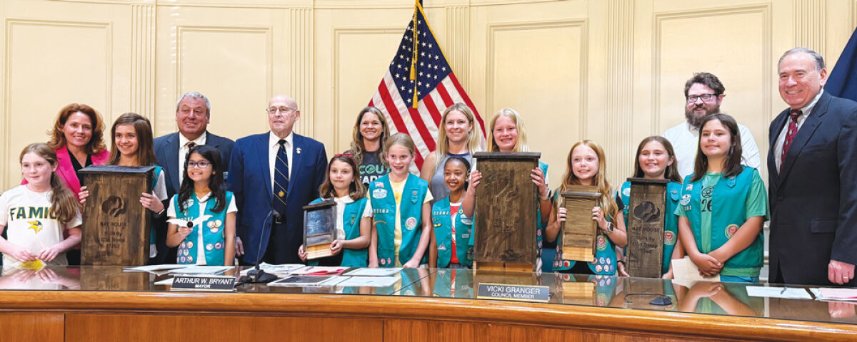  Members of Girl Scout Troop 77262 pose with the Grosse Pointe Woods City Council  and the bat houses that the scouts created for the city. 