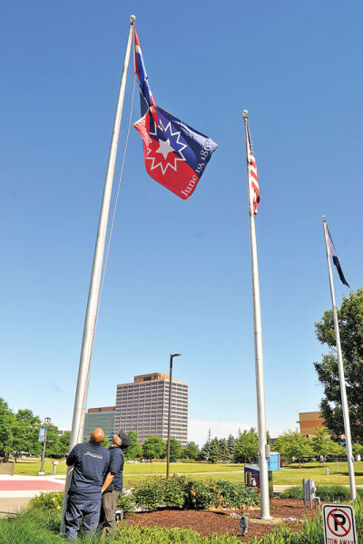  City of Southfield maintenance crew members D’Angelo Givhan, left, and Wendell Golson, right, raise the Juneteenth flag on the Southfield Municipal campus. 