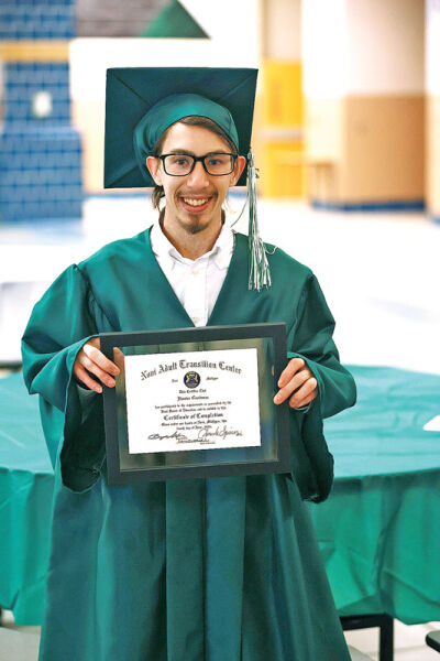  Hunter Goodman is all smiles as he shows off his certificate of completion of the Novi Adult Transition Center program on June 4. 