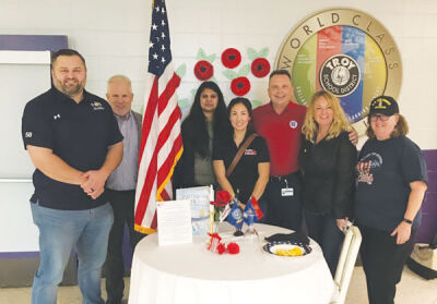  Members of the General Motors Veterans Employee Resource Group went to Boulan Park Middle School to speak to the students there about military service. They posed beside the “white table,” which is set up in memory of veterans. 