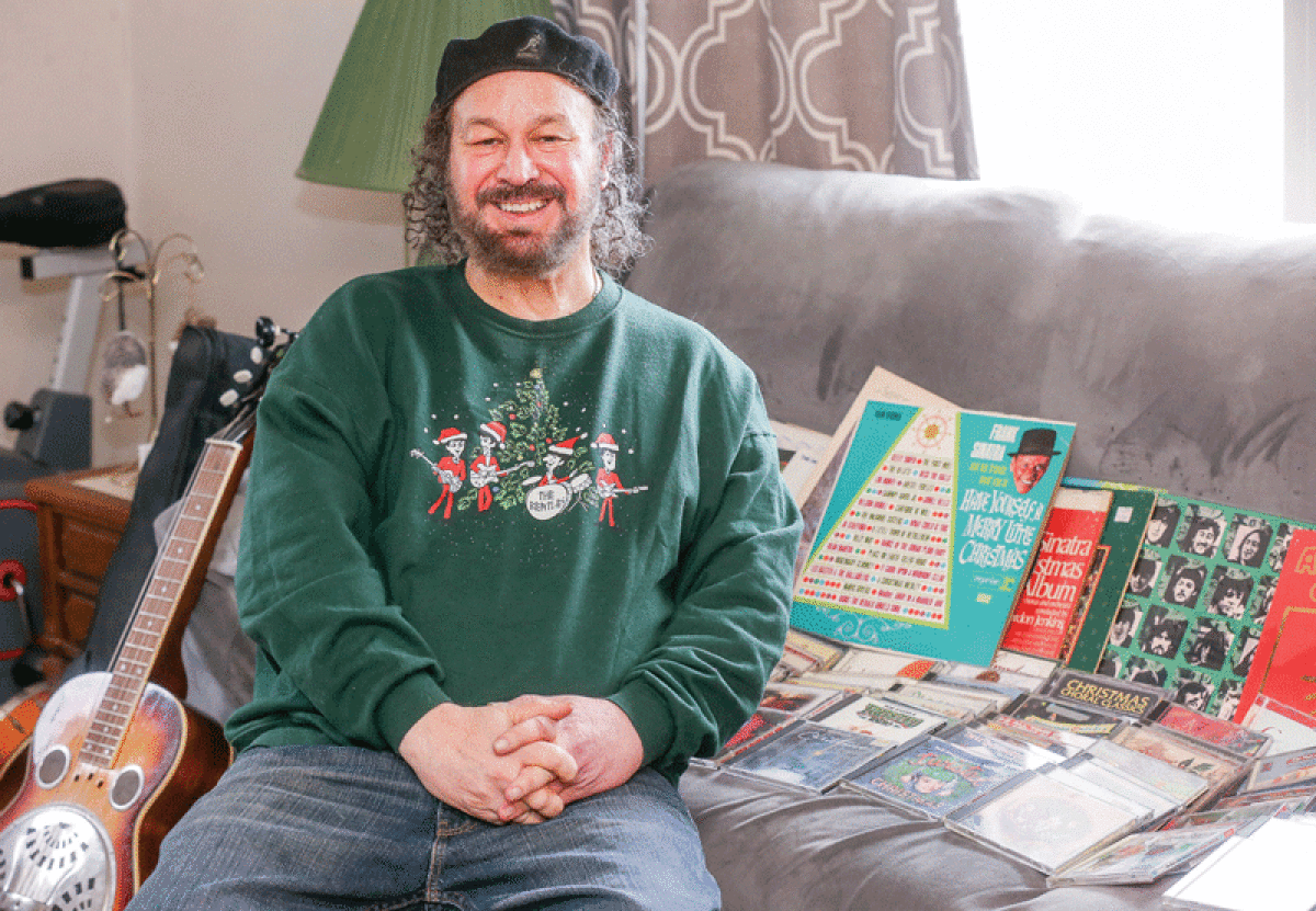   St. Clair Shores resident Vito Lafata, wearing a Christmas Beatles sweatshirt, listens to holiday music at home every year. His collection includes everyone from Frank Sinatra to the Carpenters. 